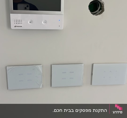 מסך אינטרקום ולחצנים על קיר, חור עם חוטים.
